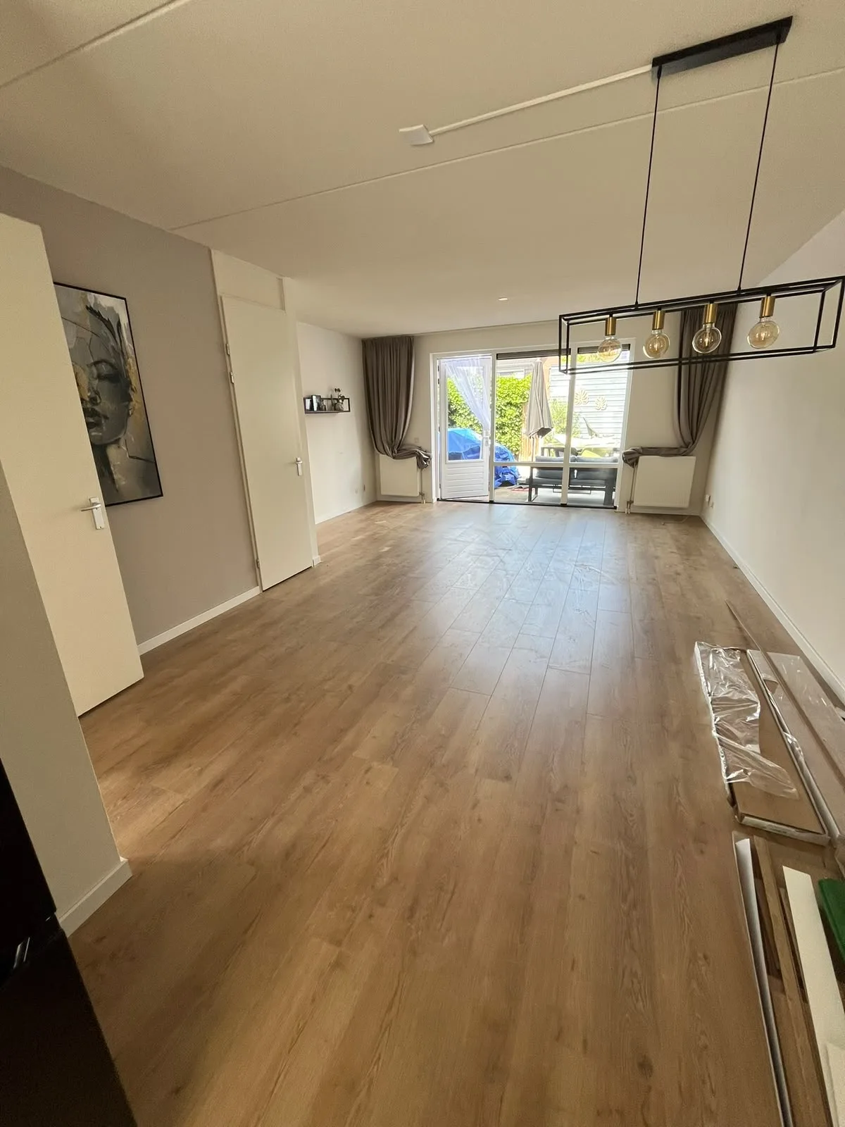 Woonkamer met doorgelegde vloer en tuindeuren